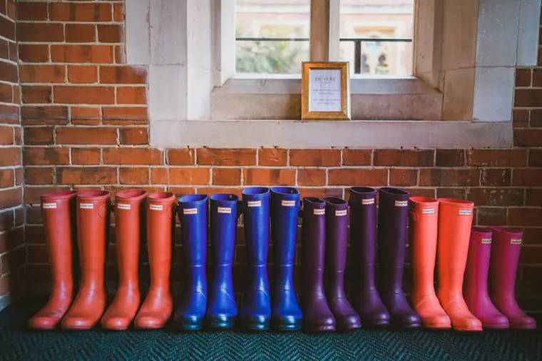 Row of colourful wellington boots lined up beneath a window