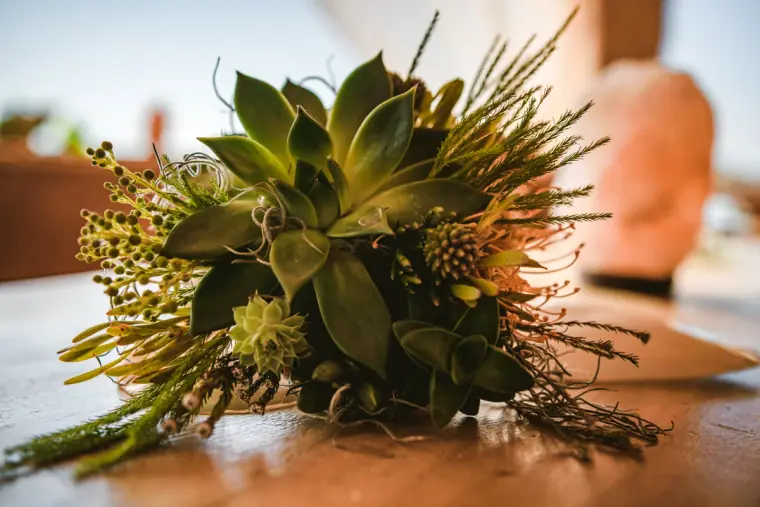Succulent and wild greenery bouquet resting on a wooden table at Sunset Ashram, Cala Conta