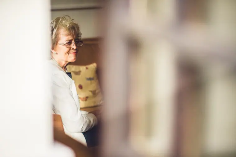 Older woman smiling in the bridal preparation room, seen past a doorway