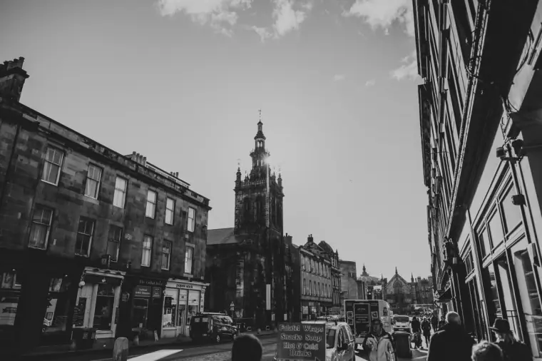Black-and-white street view of a busy Edinburgh street leading to a church tower