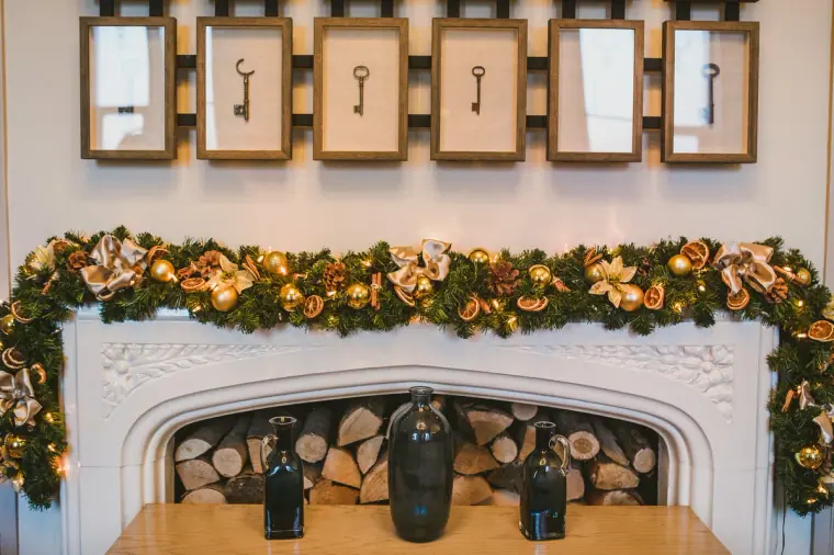 Framed antique keys above a fireplace garlanded with dried oranges and greenery