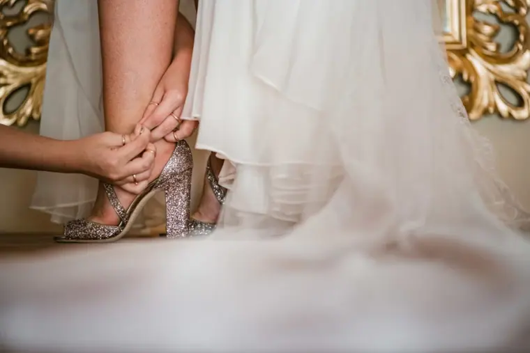 Bride being helped into her sparkly heels beneath her tulle skirt