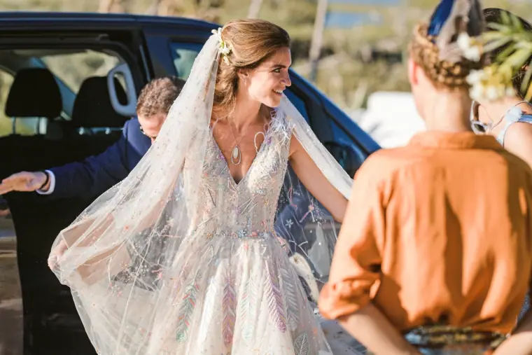Bride stepping out of the wedding car in a beaded gown and long veil at Codolar beach, Salinas