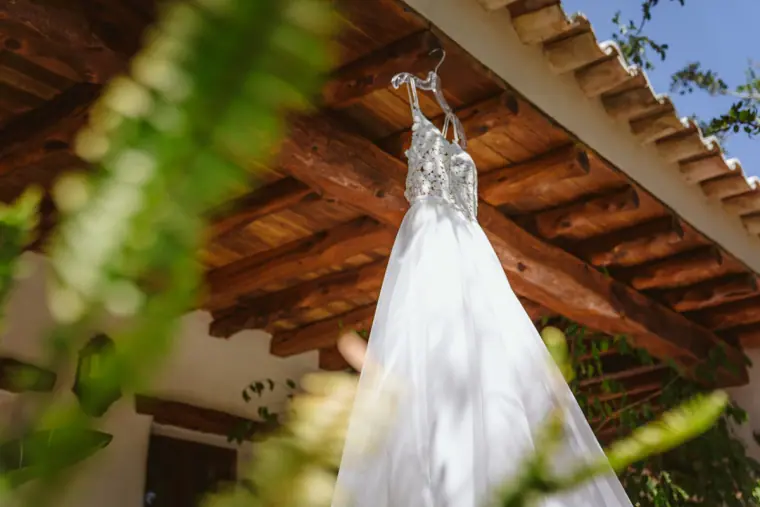 Beaded wedding dress hanging from the timber eaves of a terracotta-tiled roof