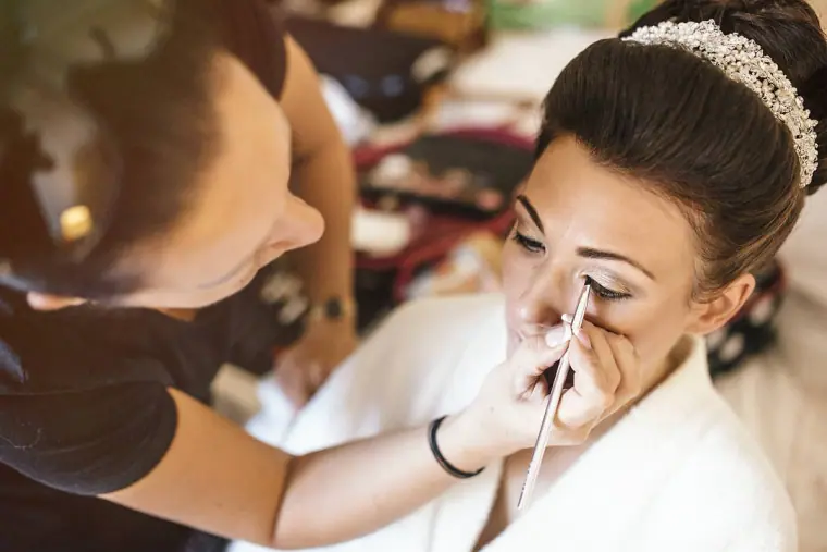 Make-up artist applying eyeliner to the bride, who wears a sparkling tiara