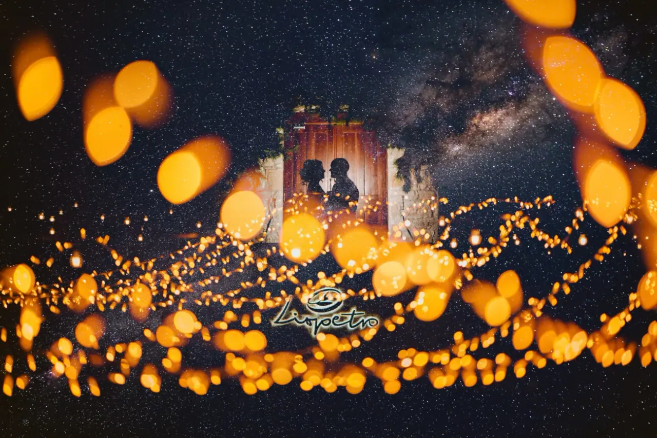 Bride and groom silhouetted in a doorway beneath a star-filled sky and golden lights, Liopetro, Kouklia