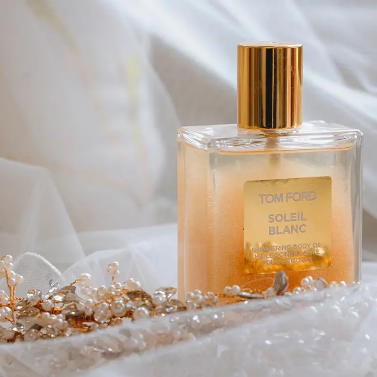 Bottle of Tom Ford Soleil Blanc perfume beside a jewelled hairpiece
