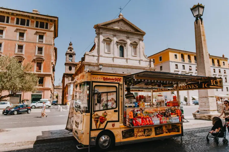 Vintage snack van parked in a Rome piazza in front of a baroque church facade