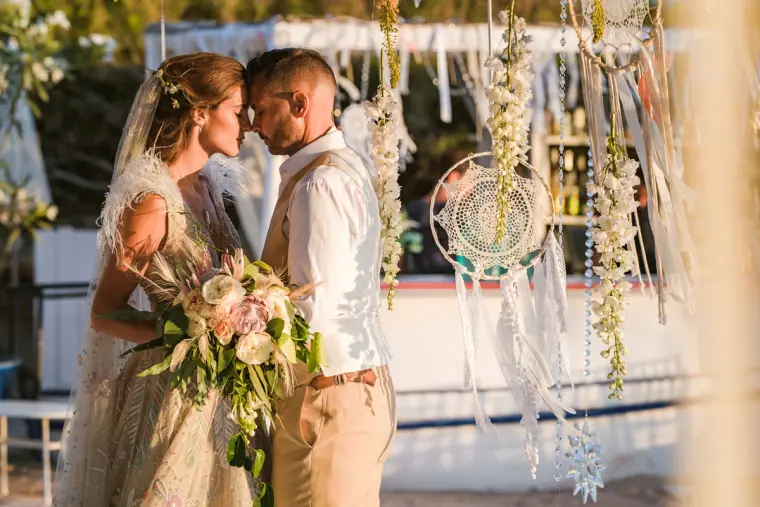 Couple touching foreheads among hanging dreamcatchers and flowers