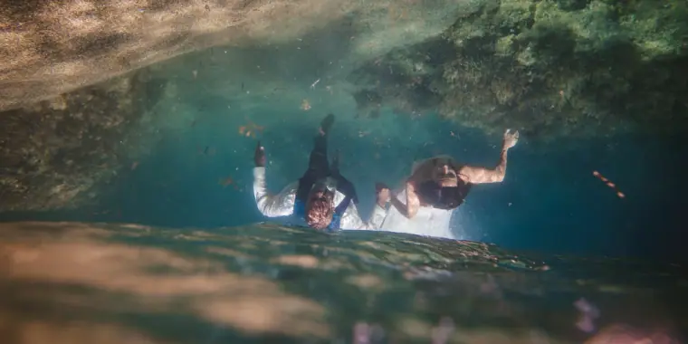 Bride and groom swimming underwater in their wedding clothes