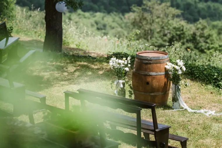 Wine barrel altar with white flowers and wooden benches on a hillside lawn at Livernano Estate