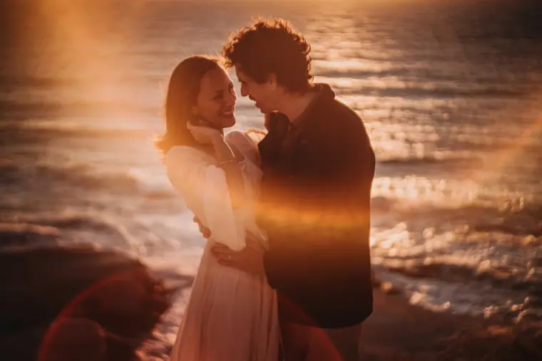 Aiko and Erez touching foreheads in warm sunset light by the sea