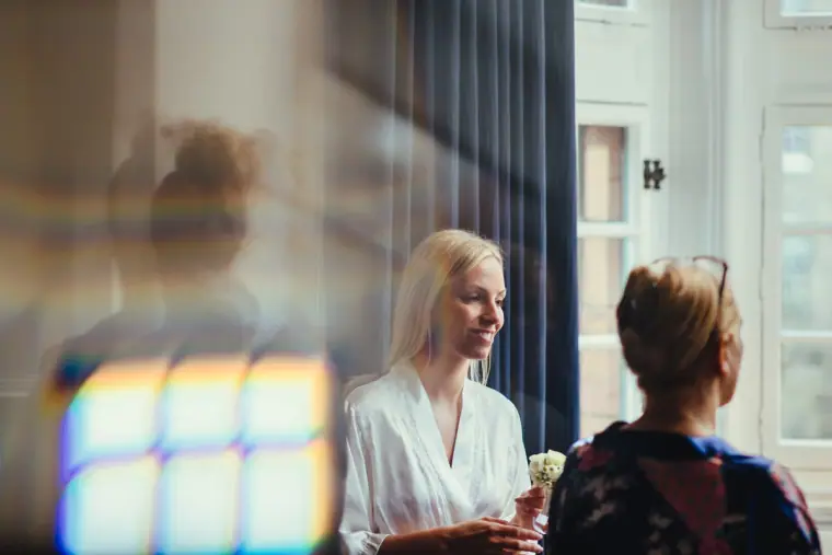 Bridesmaids chatting with drinks in a tall-windowed room