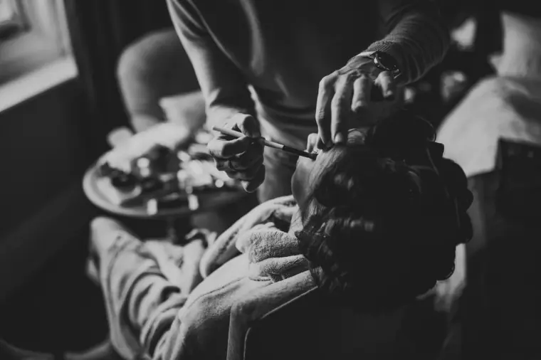 Black-and-white close-up of hands during the bride's hair and make-up