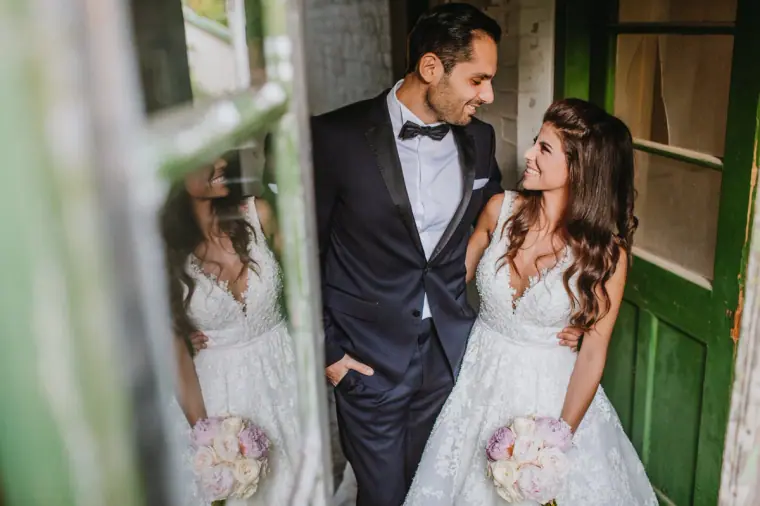 Couple smiling at each other in a green doorway, reflected in the window glass, Four Seasons Limassol