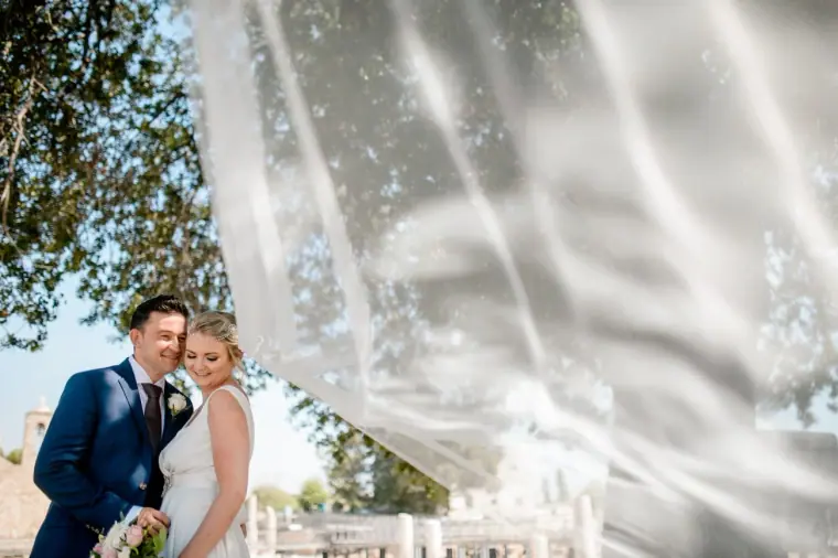 Francesca and Stephen framed by a drifting veil among the ruins at Ayia Kyriaki