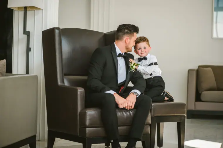 Steven in a leather armchair beside a young page boy in a matching bow tie
