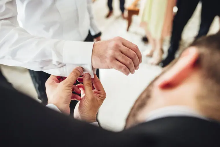 Close-up of hands fastening the groom's cufflink
