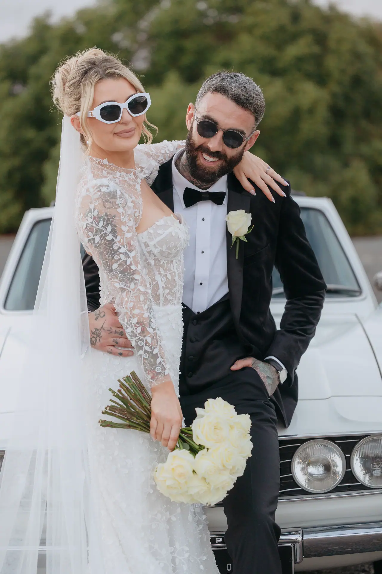 Bride and groom in sunglasses sitting on the Triumph Stag, Cyprus