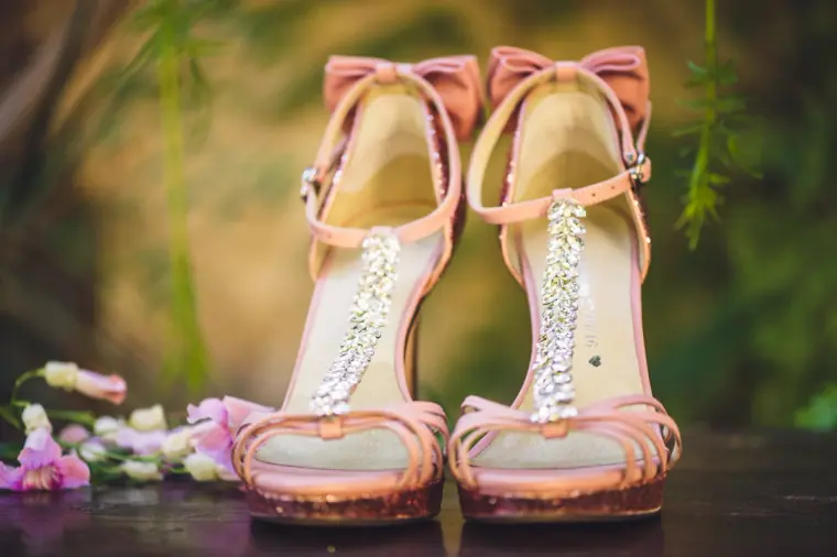 Pink glitter heels with jewelled straps among scattered petals