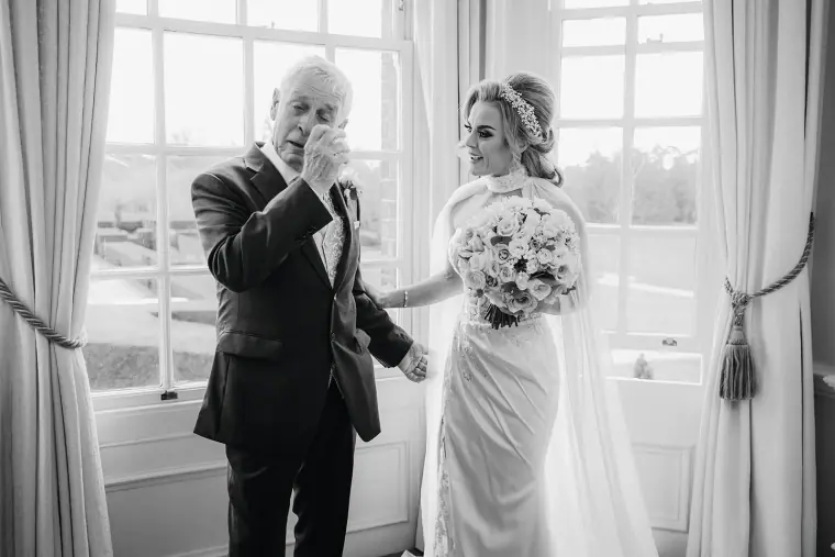 Black-and-white photo of Jade's father wiping a tear as he sees her