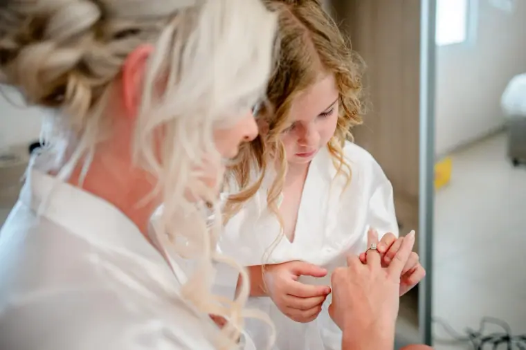 Flower girl holding the bride's hands as her hair is finished