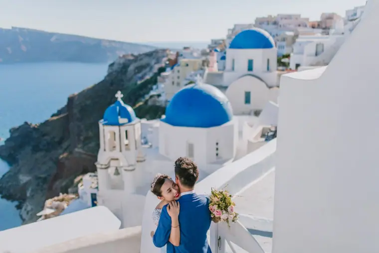 Couple sharing a kiss above the famous blue-domed churches of Santorini