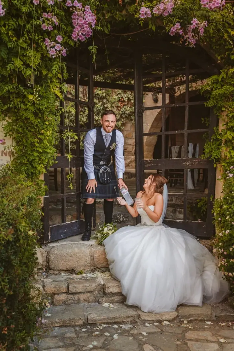 Keith standing behind Hannah, seated in her gown under a bougainvillea pergola