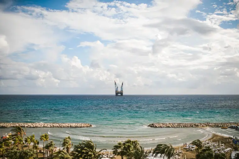 Turquoise sea, breakwaters and palm-lined beach under a cloudy sky