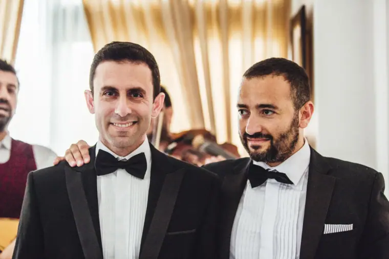 Angelos and his best man smiling in black tuxedos and bow ties