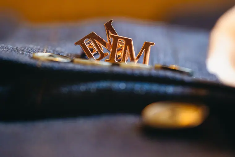 Gold monogram initials pinned to the groom's navy suit