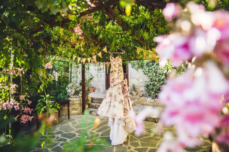 Pink-and-white floral wedding gown hanging under the vine pergola at Vasilias Nikoklis Inn