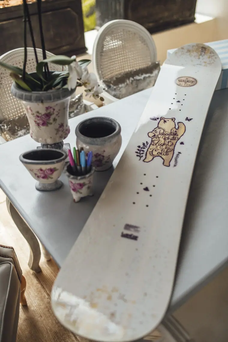 Decorated snowboard guest book beside potted orchids and pens
