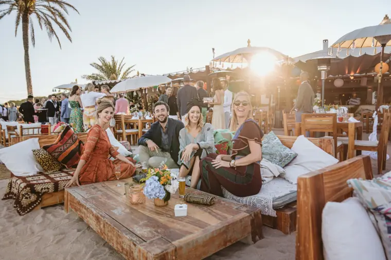 Guests relaxing on cushioned beach loungers at sunset at Restaurante La Escollera, Ibiza