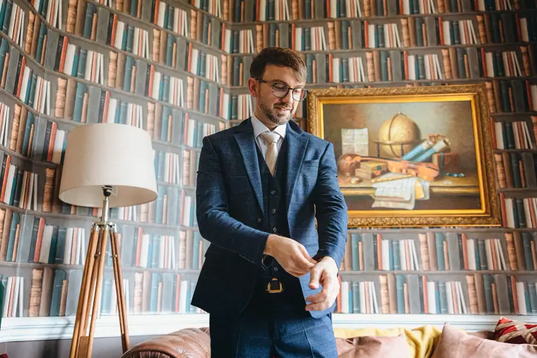 Ian fastening his cuffs in a book-lined room at Hedsor House
