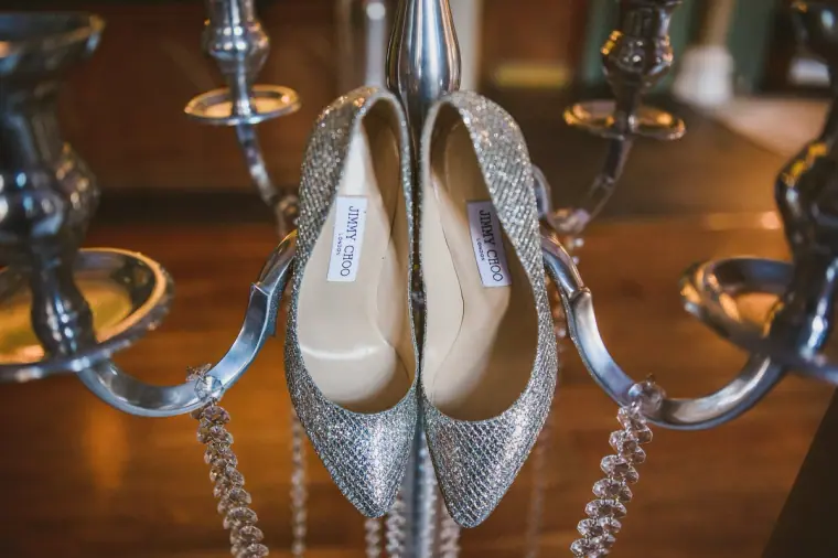 Sparkly silver Jimmy Choo heels hanging from a silver candelabra
