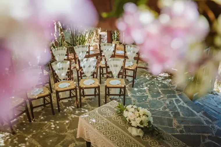 Ceremony area with rush-seat chairs and a white bouquet seen through pink blossom