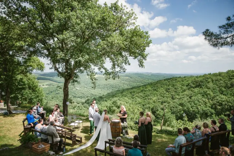 Outdoor ceremony on a hillside overlooking green Tuscan valleys at Livernano Estate