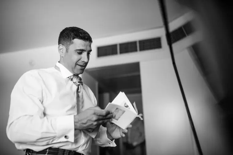 Groom in shirt and tie reading a card from the bride