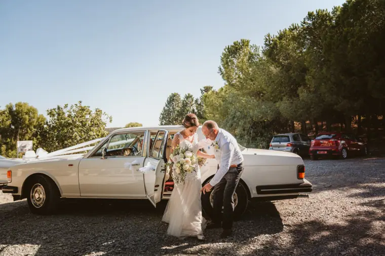 Father helping the bride out of a white vintage Rolls-Royce