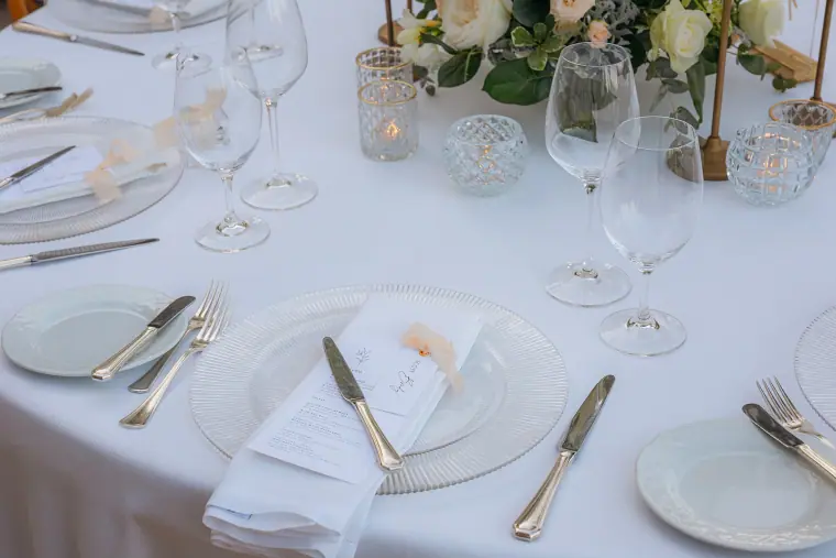 Place setting with a glass charger, folded napkin and name card