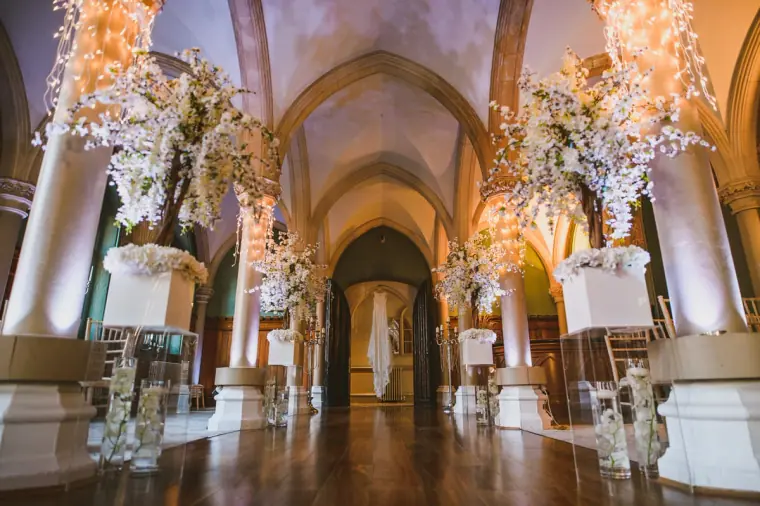 Vaulted hall at Wotton House decorated with white blossom trees and candles
