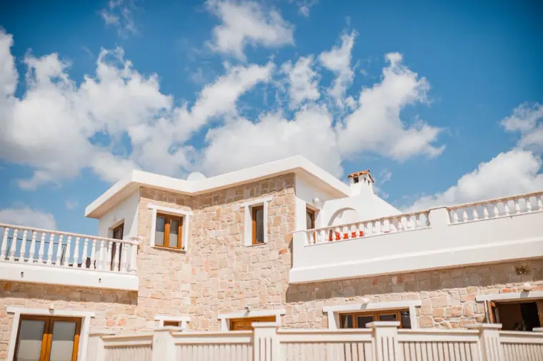 Stone villa with white balconies against a bright blue sky at Minthis Hills