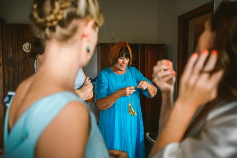 Woman in a turquoise dress laughing with bridesmaids as they get ready