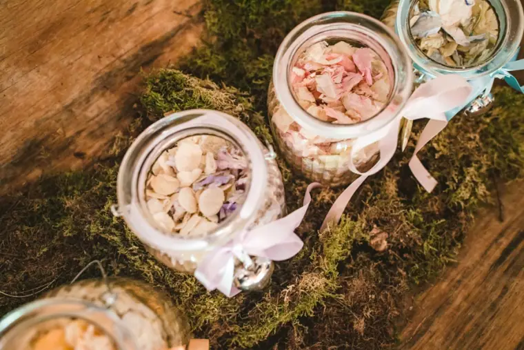 Jars of dried petal confetti tied with ribbon on a bed of moss