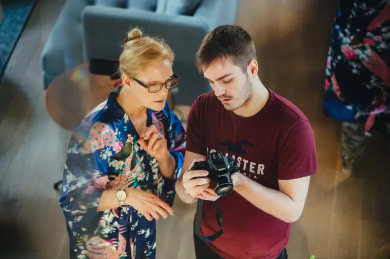 Bridesmaid and a young man checking a camera together during preparations