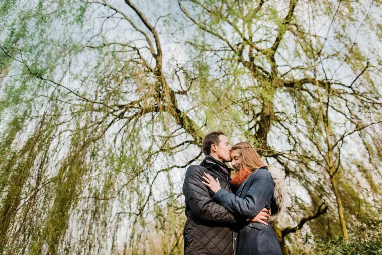 Couple embracing beneath trailing willow branches