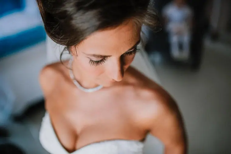 Close-up of a bride looking down, wearing a delicate necklace, Galu Seaside