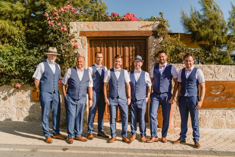 Groom and groomsmen in navy waistcoats lined up by the gate at Liopetro, Kouklia
