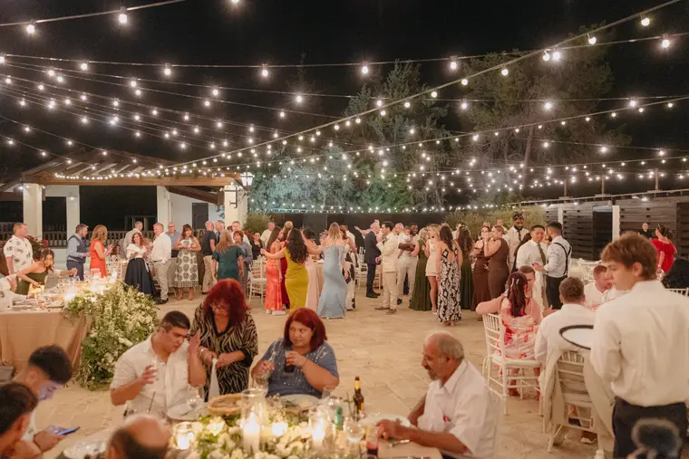Guests dancing and dining under festoon lights at the evening reception